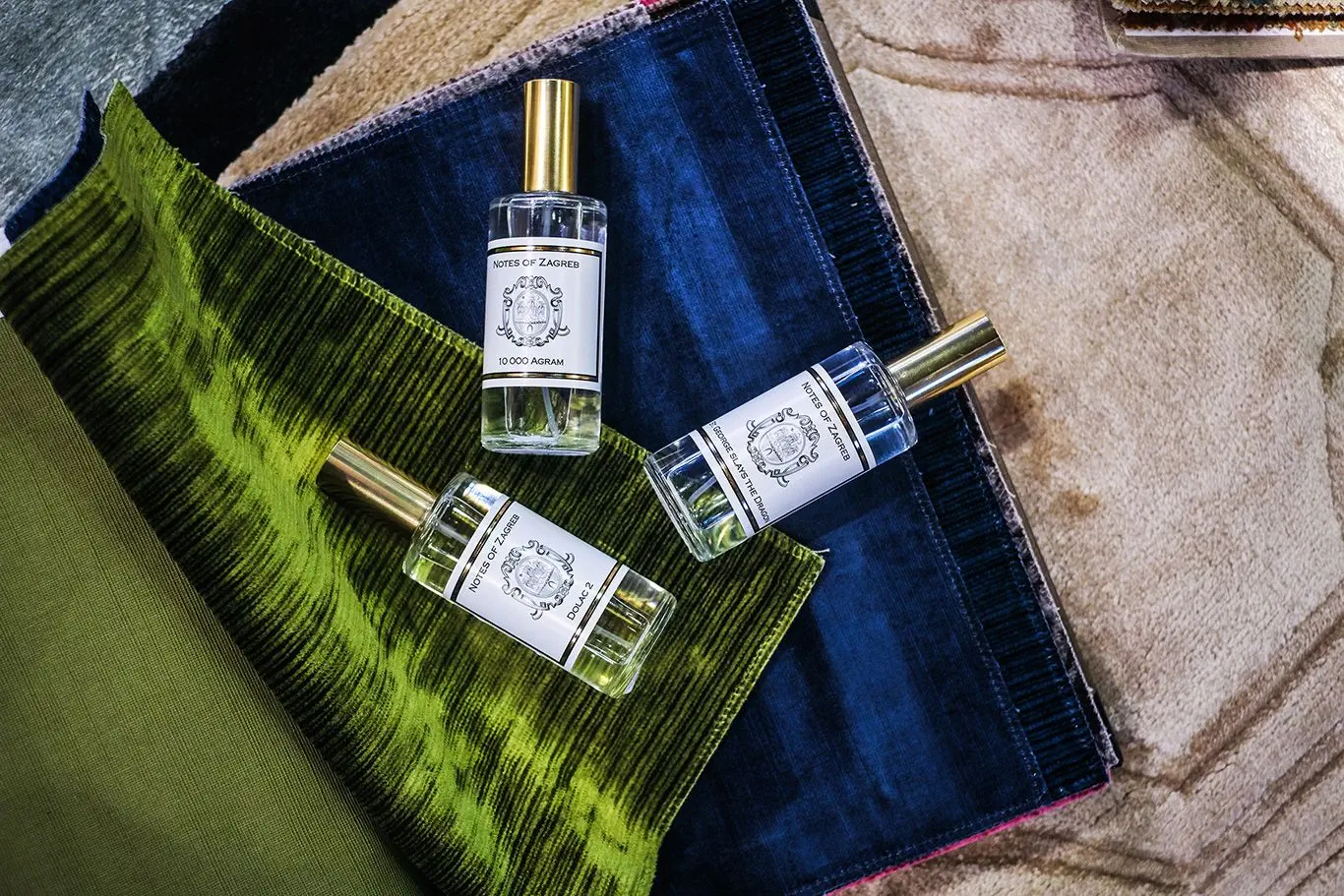 Three Notes of Zagreb perfume bottles on blue velvet fabric display