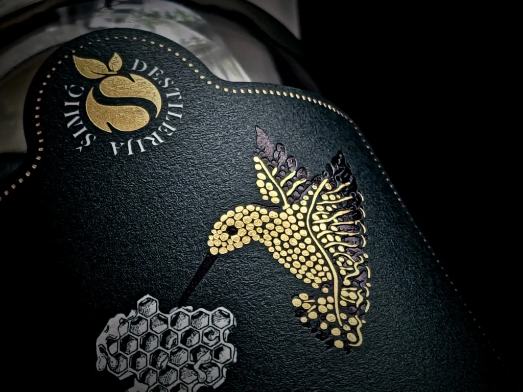 Simic Destilerija black bottle label with gold hummingbird and honeycomb design